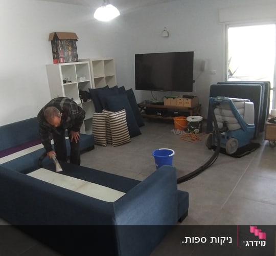 אדם מנקה ספה עם מכונת ניקוי ושואב אבק